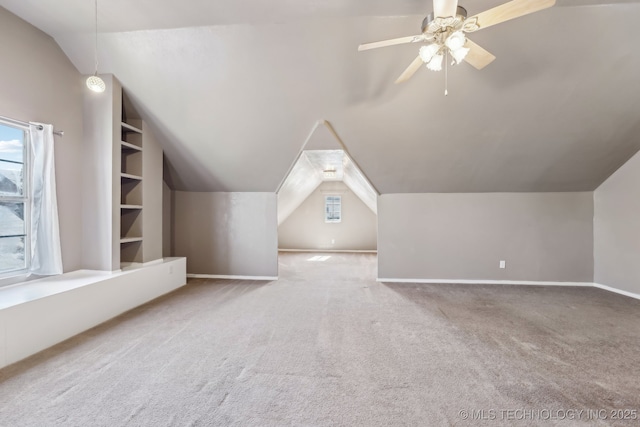 bonus room with vaulted ceiling, carpet flooring, plenty of natural light, ceiling fan, and built in shelves
