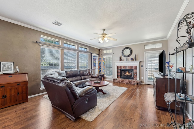 living room featuring ceiling fan, a textured ceiling, hardwood / wood-style floors, ornamental molding, and a textured wall