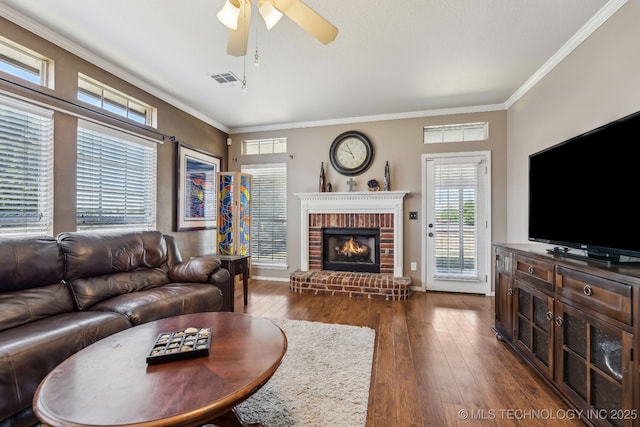 living area featuring dark wood-style flooring, ceiling fan, a fireplace, crown molding, and baseboards