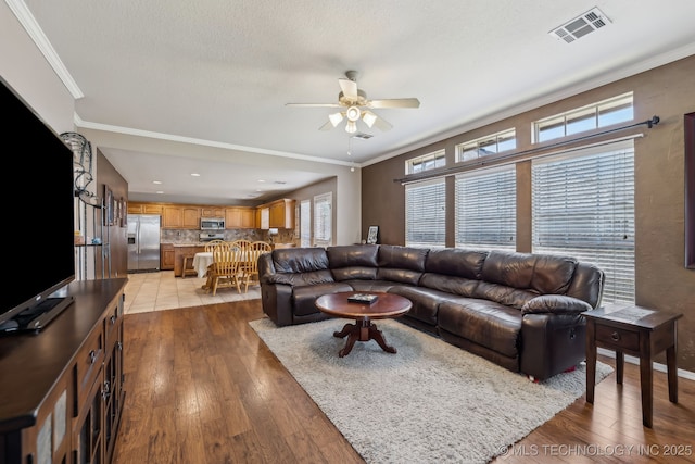 living area with ceiling fan, wood-type flooring, and crown molding