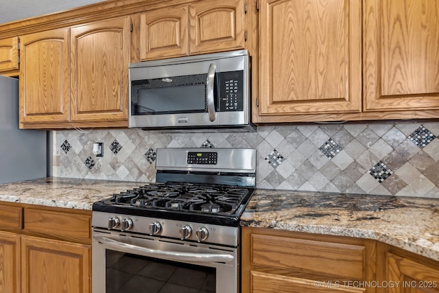 kitchen featuring appliances with stainless steel finishes, backsplash, and light stone countertops