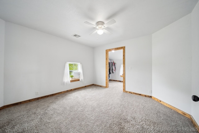carpeted empty room with a ceiling fan and baseboards