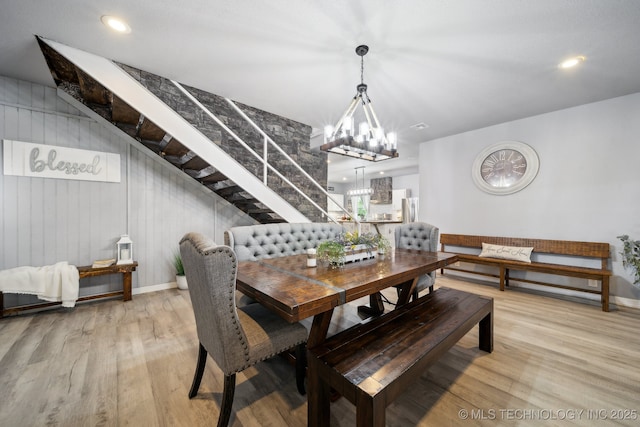dining space with wood finished floors, a chandelier, stairs, and baseboards