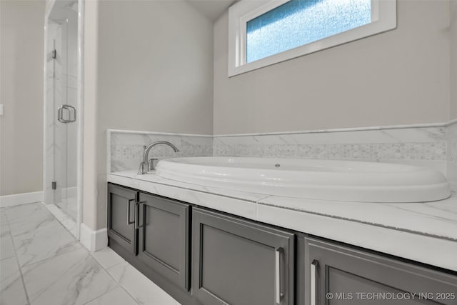 full bath with marble finish floors, a shower stall, a garden tub, and baseboards