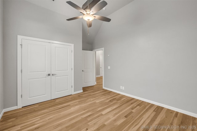 unfurnished bedroom with light wood-type flooring, baseboards, a closet, ceiling fan, and high vaulted ceiling