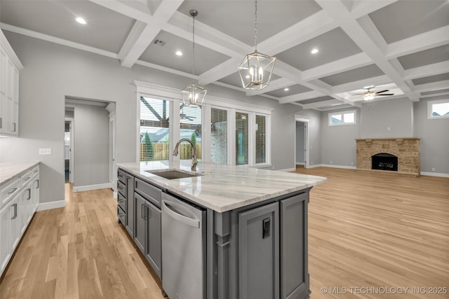kitchen with a sink, dishwasher, gray cabinetry, a fireplace, and a chandelier