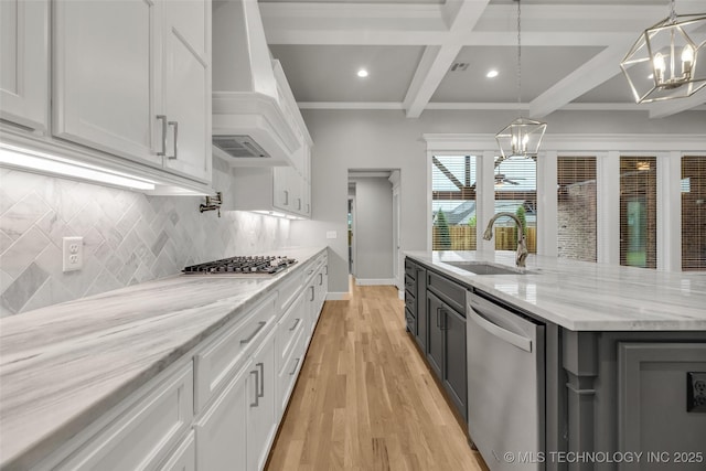 kitchen featuring stainless steel appliances, a sink, a chandelier, white cabinetry, and custom range hood