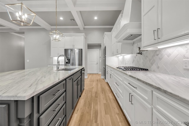 kitchen with custom range hood, a sink, appliances with stainless steel finishes, beam ceiling, and white cabinets