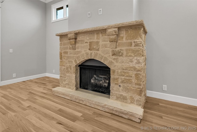 detailed view of baseboards, wood finished floors, and a fireplace with raised hearth