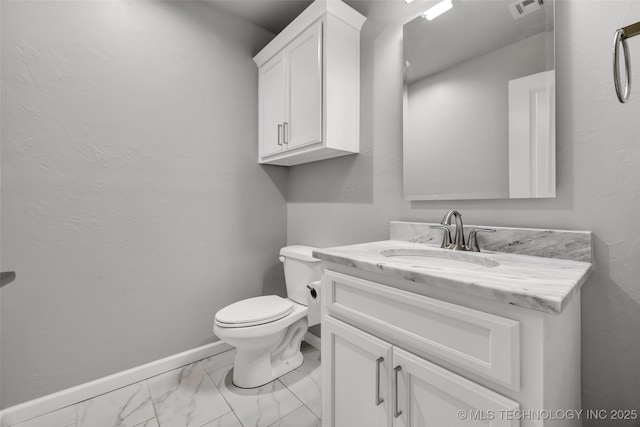 half bathroom with marble look tiles, vanity, baseboards, and toilet