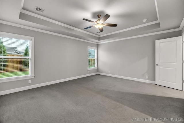 carpeted spare room featuring a raised ceiling, crown molding, ceiling fan, and baseboards