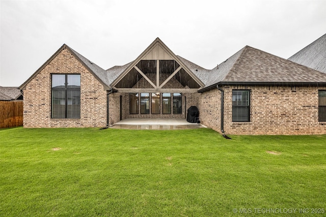 back of property with brick siding, a shingled roof, and a patio area