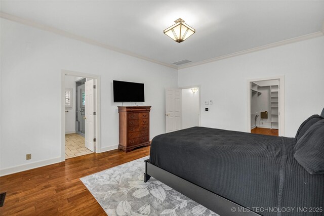 9304 E 113th St S, Bixby, OK 74008 - bedroom with wood finished floors, crown molding, a spacious closet, and connected bathroom