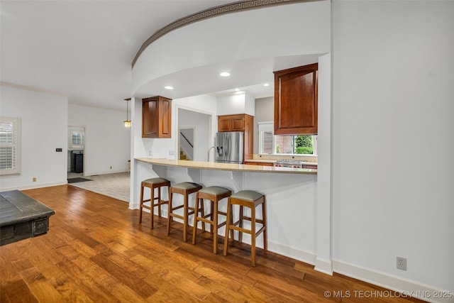 9304 E 113th St S, Bixby, OK 74008 - kitchen with stainless steel fridge with ice dispenser, wood finished floors, a breakfast bar, plenty of natural light, and recessed lighting