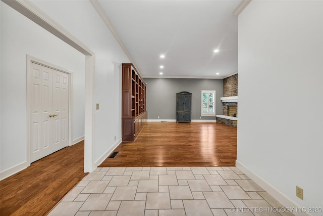 9304 E 113th St S, Bixby, OK 74008 - unfurnished living room featuring a stone fireplace, recessed lighting, ornamental molding, and light wood-style floors