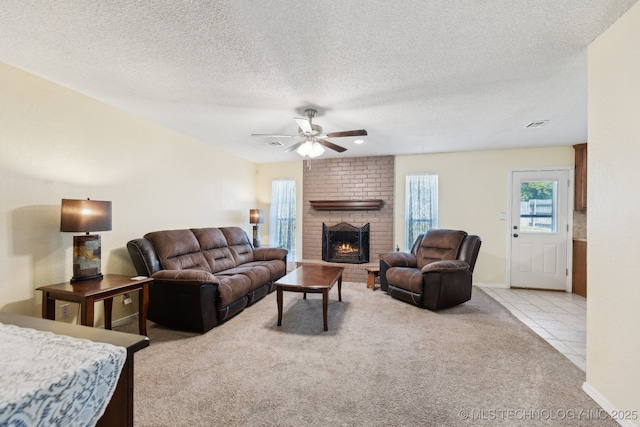 living area with light colored carpet, a ceiling fan, a brick fireplace, a textured ceiling, and baseboards