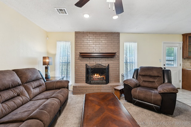 carpeted living room with a ceiling fan, a brick fireplace, a textured ceiling, and recessed lighting