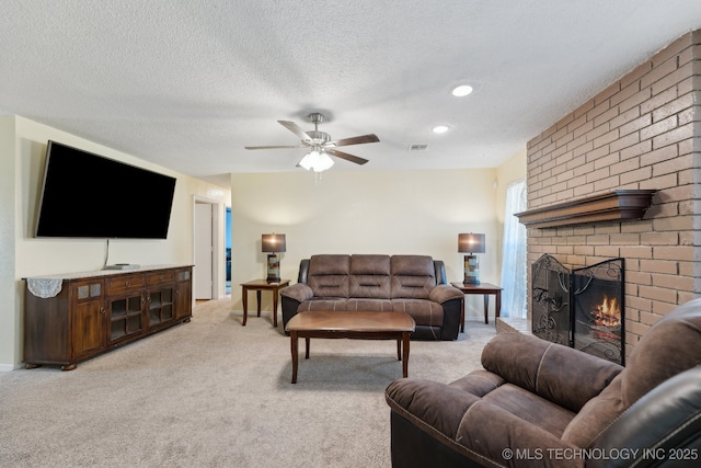 living area with a ceiling fan, a brick fireplace, light carpet, and a textured ceiling