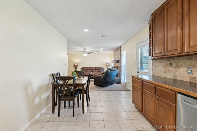 kitchen with dark countertops, brown cabinets, tasteful backsplash, a ceiling fan, and a fireplace