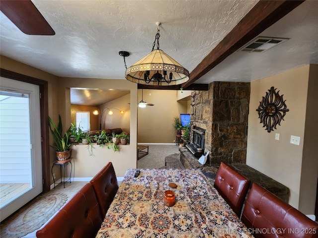 14360 County Road 3505th Loop, Ada, OK 74820 - carpeted dining space with a ceiling fan, baseboards, a stone fireplace, and beam ceiling