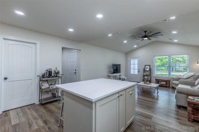kitchen featuring open floor plan, a center island, wood finished floors, ceiling fan, and lofted ceiling