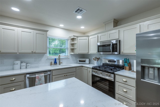 kitchen featuring stainless steel appliances, a sink, tasteful backsplash, light stone countertops, and recessed lighting