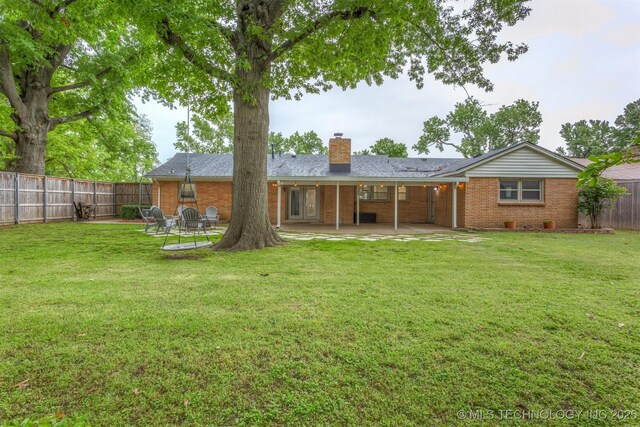 rear view of house with brick siding, a chimney, and a patio area