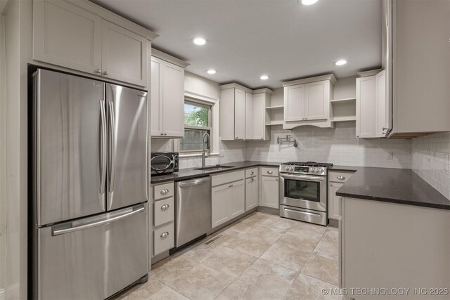 kitchen with appliances with stainless steel finishes, open shelves, a sink, decorative backsplash, and recessed lighting