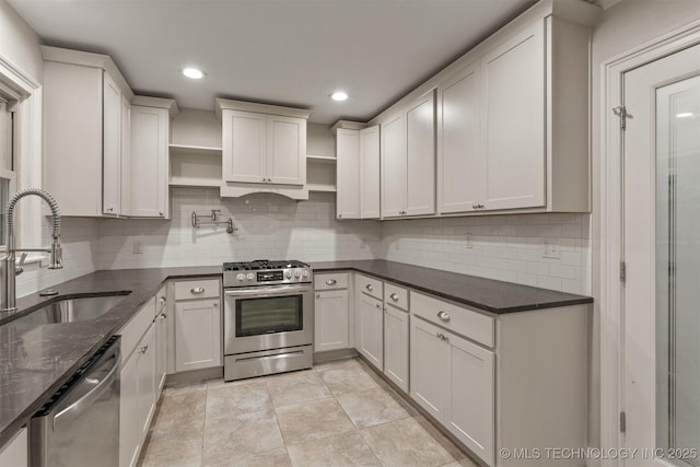 kitchen featuring appliances with stainless steel finishes, open shelves, a sink, backsplash, and dark stone counters