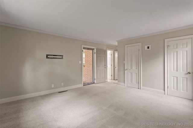 carpeted empty room featuring crown molding and baseboards