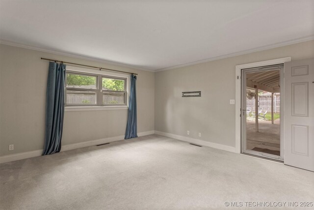 carpeted spare room featuring crown molding, plenty of natural light, and baseboards