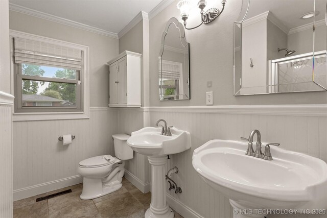 full bathroom with toilet, a sink, a shower, a wainscoted wall, and crown molding