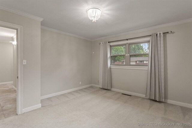 carpeted spare room featuring ornamental molding, baseboards, and a chandelier
