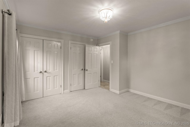 unfurnished bedroom with two closets, carpet, crown molding, and baseboards