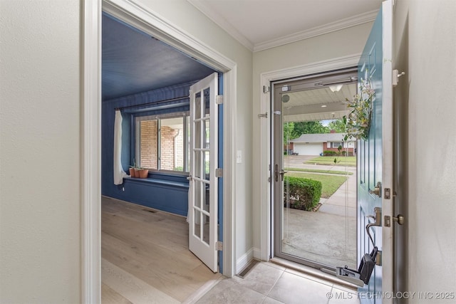 foyer entrance with ornamental molding, french doors, baseboards, and light wood-style floors