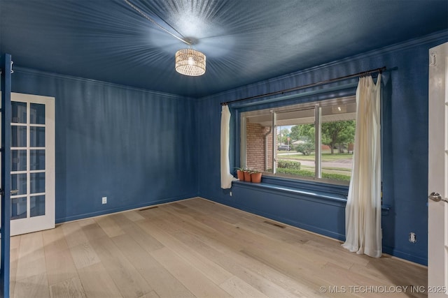 unfurnished room featuring wood finished floors, a chandelier, and ornamental molding
