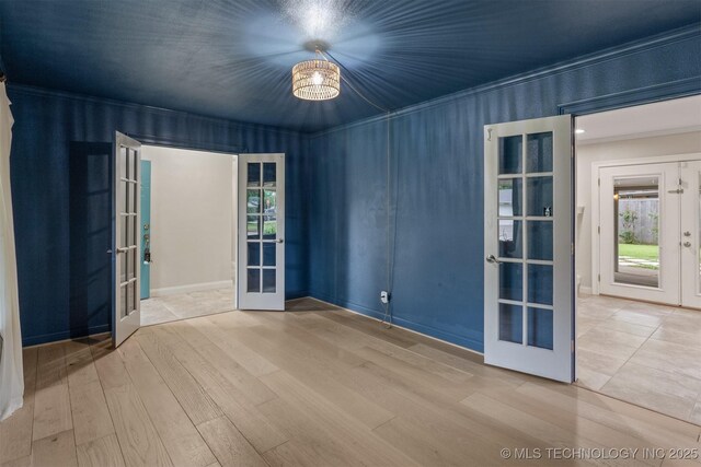 spare room featuring french doors, healthy amount of natural light, wood finished floors, and crown molding