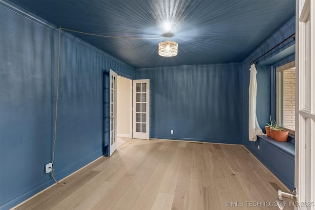 empty room featuring wood finished floors, french doors, and baseboards