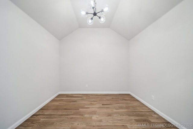 bonus room with a chandelier, vaulted ceiling, wood finished floors, and baseboards
