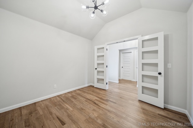 unfurnished bedroom with lofted ceiling, a chandelier, wood finished floors, french doors, and baseboards