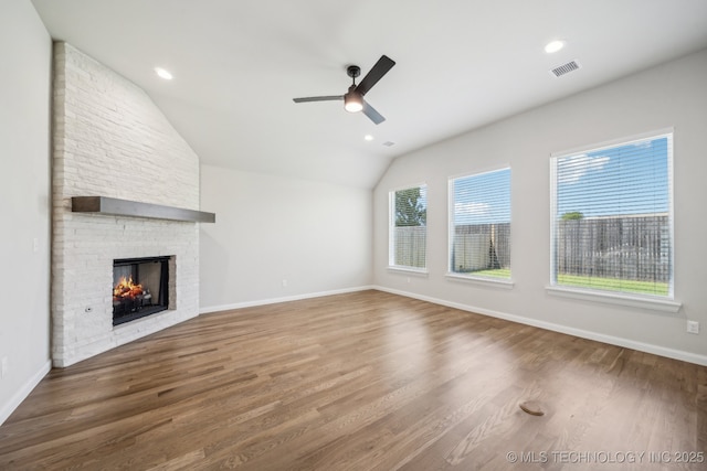 unfurnished living room featuring ceiling fan, lofted ceiling, a fireplace, wood finished floors, and baseboards