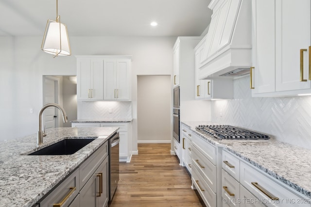kitchen with premium range hood, a sink, stainless steel appliances, white cabinetry, and backsplash