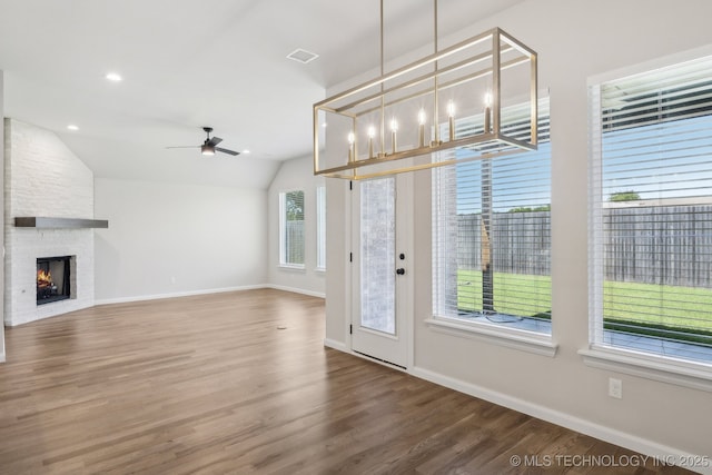 unfurnished living room featuring a ceiling fan, wood finished floors, a fireplace, baseboards, and vaulted ceiling