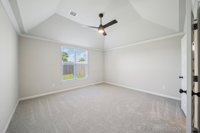 carpeted spare room with a ceiling fan, vaulted ceiling, baseboards, and crown molding