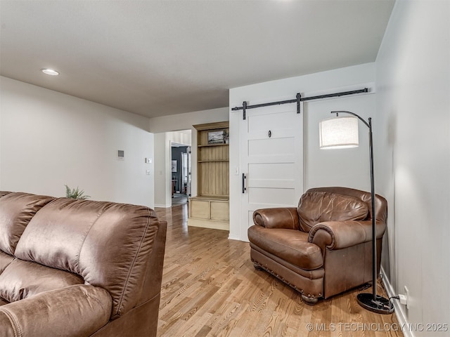 living room with a barn door, light wood-style flooring, baseboards, and recessed lighting