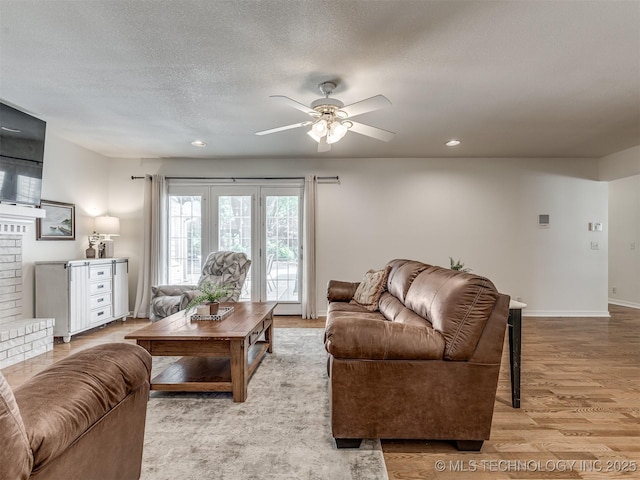 living room featuring light wood-style flooring, ceiling fan, baseboards, a textured ceiling, and recessed lighting