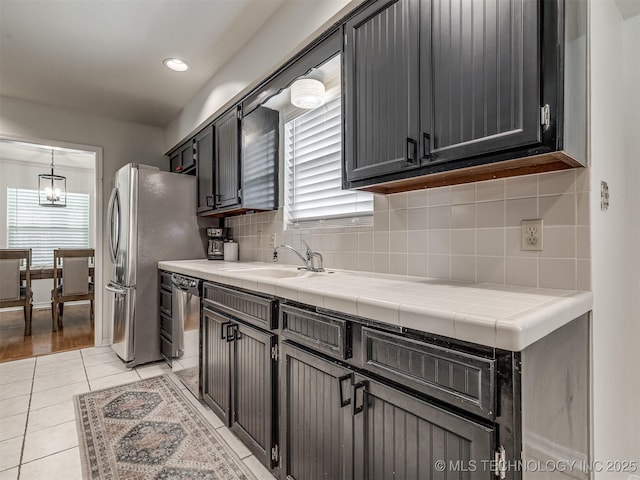 kitchen with a sink, stainless steel appliances, decorative backsplash, light tile patterned floors, and recessed lighting