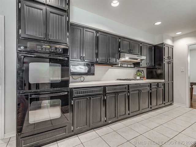 kitchen featuring black appliances, under cabinet range hood, light countertops, light tile patterned flooring, and decorative backsplash