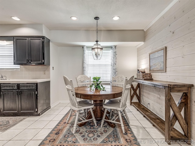 dining space with light tile patterned floors, wood walls, and recessed lighting