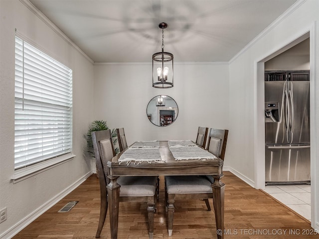 dining area featuring plenty of natural light, crown molding, a chandelier, baseboards, and light wood-style floors